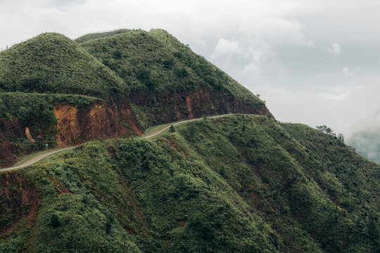 A winding road snakes through lush green hills under a cloudy sky. Binh Lieu District, Quang Ninh, Vietnam