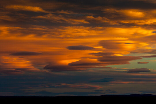 Dramatic orange and gold sunset clouds create a vibrant, striking sky over a dark landscape. Calgary, Canada