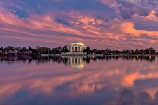 The Jefferson Memorial at sunset reflected in the calm waters with a dramatic sky above. Washington DC, WA, USA