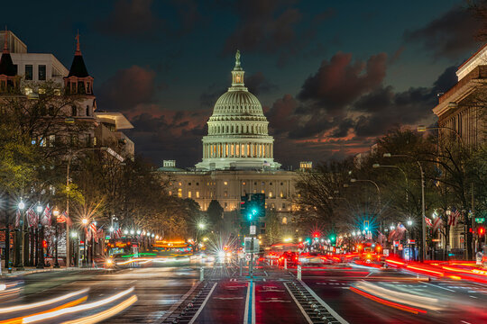 View of the US Capitol building at dusk with blurred traffic lights in the foreground. Washington DC, WA, USA