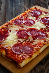 Pepperoni pizza with salami, tomato sauce and mozzarella cheese on wooden table	