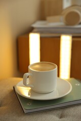 Coffee, notebook on pouf and portable LED lamps at home, closeup