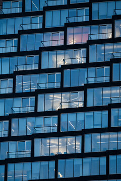 Modern building facade with staggered windows and balconies at dusk. Calgary, Alberta, Canada