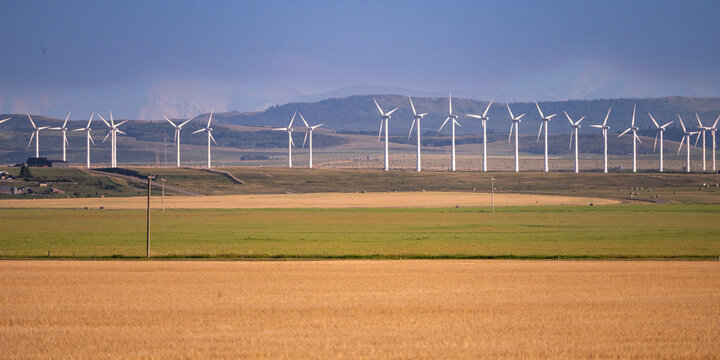 Wind turbines on a vast landscape with fields under a clear sky in the distance. Waterton Lakes National Park, Alberta, Canada