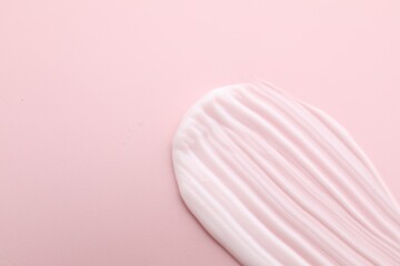Sample of moisturizing cream on pink background, top view. Space for text