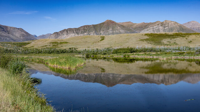 Serene mountain landscape with clear blue sky and still water reflection. Waterton Park, Alberta, Canada