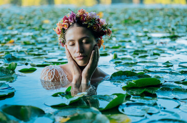 Woman in a floral crown peacefully floating among water lilies with eyes closed. Wildcat Lake Park, WA, USA