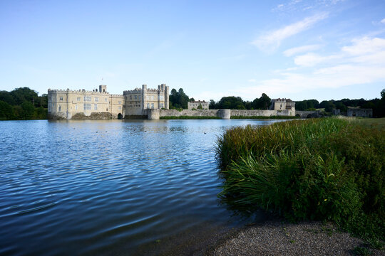 Leeds Castle, majestic castle by a serene lake under a bright blue sky with lush greenery. Kent, UK