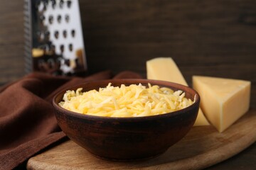 Grated and pieces of cheese on wooden table, closeup