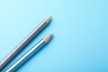Eye pencils on light blue background, flat lay. Space for text