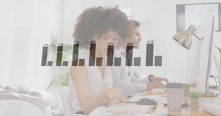 Typing colleagues in business attire analyzing data on monitors in office, with bar chart overlay
