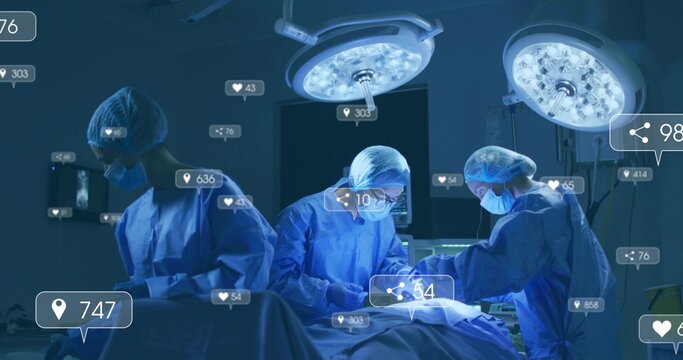 Operating surgeons wearing blue gowns using table, instruments and digital icons, in hospital OR