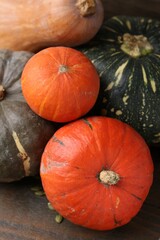 Many fresh pumpkins and seeds on wooden table, closeup. Gourd family