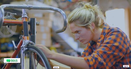 Truing female mechanic adjusting bicycle wheel in repair workshop, with road bike and toolbox