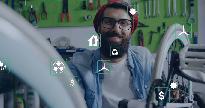 Sitting bike mechanic wearing red beanie fixing wheel at shop with tools, showing sustainable icons - Powered by Adobe
