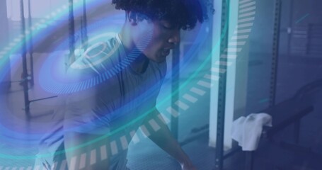 Bending forward fit man lifting weights inside gym with squat rack, rubber mats and digital overlay