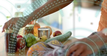 Reaching forearms wearing orange shirt on wooden countertop, handling fresh produce and pantry jars