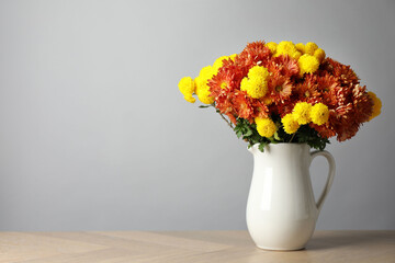 Autumn atmosphere. Vase with beautiful flowers on wooden table, space for text