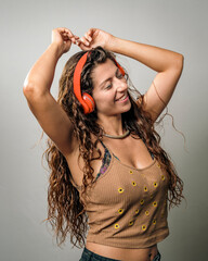 Joyful young woman enjoying music while dancing with vibrant headphones on a clean background