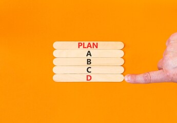 Time to plan D symbol. Concept word Plan A B C D on beautiful wooden sticks. Businessman's hand. Beautiful orange background. Business planning and time to plan D concept. Copy space.