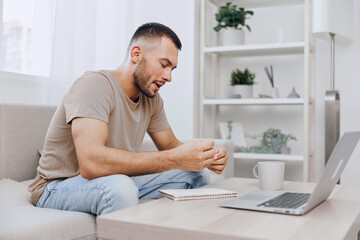 Concentrated man engaging in creative brainstorming at home, surrounded by a cozy environment, laptop and notebook in front, demonstrating a modern workspace vibe.