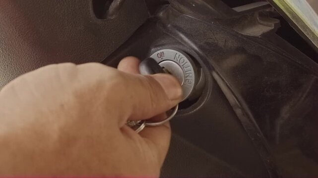 Close-up hand turning motorcycle key to the ignition ON position