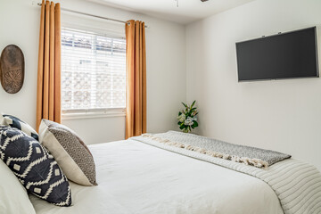 Modern desert bedroom interior. Flat screen TV, bed, accent pillows