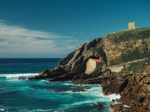 Photo of a church built under a rock facing the ocean