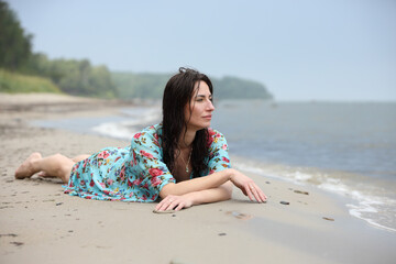 Woman in floral blue dress relaxing on beach