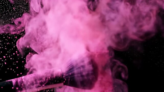 A makeup brush explodes pink powder on a black background, creating a cloud effect