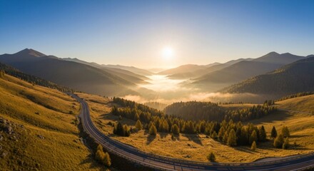 Scenic aerial view of mountains with a road winding through valleys at sunrise
