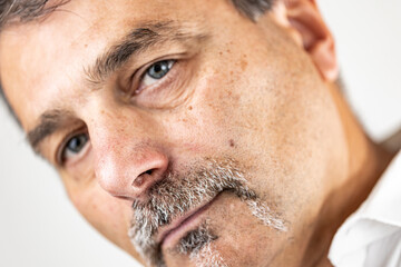 Detailed close-up of a middle-aged man with gray facial hair and an inquisitive expression, head slightly tilted in doubt.