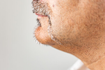 Detailed close-up image capturing the lower face and neck of an adult male, highlighting natural facial hair patterns and skin texture.
