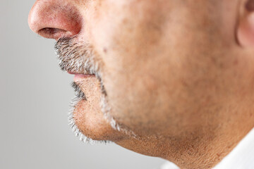 Macro side view of a man’s face showing gray mustache and goatee.