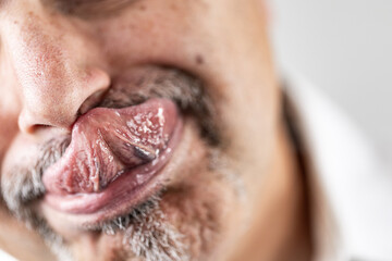 Mature man reaching and touching his nose with his tongue