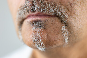 Close up of male mouth with salt and pepper facial hair.