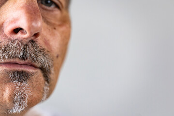 Macro portrait of a part of a man’s face focusing on his gray mustache and goatee. Sad, depressed expression. Background space for copy text.