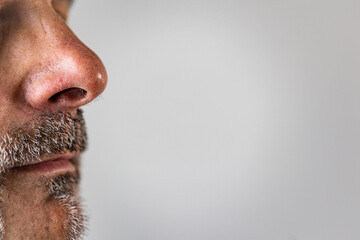 Side close-up of a man’s nose and mouth with visible facial hair and detailed skin texture.