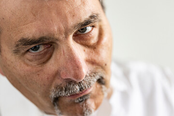 Extreme close-up of a mature man’s face showing intense gaze and natural texture. Realistic portrait emphasizing emotion, facial features, and fine details such as pores, wrinkles, and facial hair.