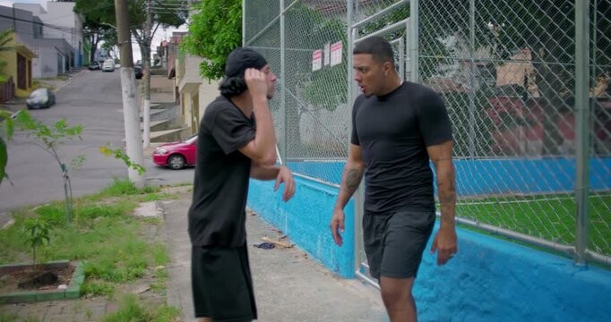 Two Hispanic men outdoors in tense confrontation escalating into argument and physical altercation, intense emotions, anger, conflict, street tension, raw human drama and aggression