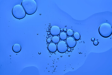 The texture of a cosmetic serum with bubbles on a blue background.