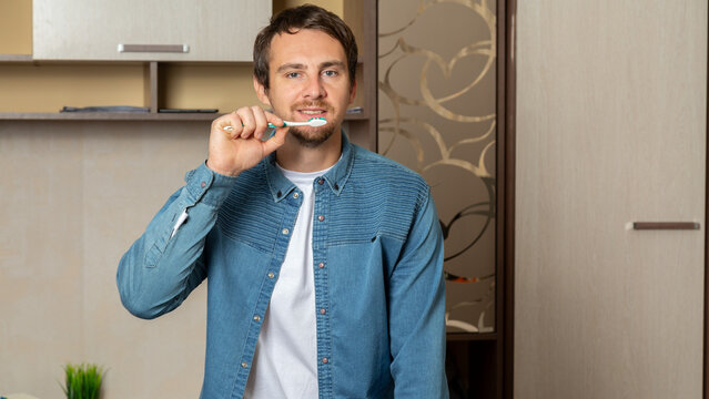 Young man brushing his teeth with a smile