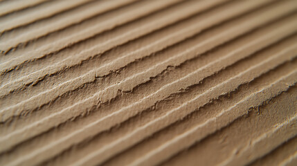 Close-up of textured, ridged material in shades of brown.  A design of layered texture with rough ridges and smooth grooves creates a structured, earthy aesthetic.