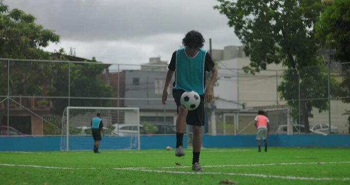 Hispanic man juggling soccer ball performing kick ups on turf field during training session, showing control, balance and focus while practicing footwork in outdoor park - Powered by Adobe