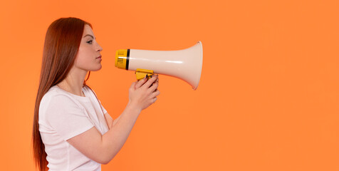 Young woman holds megaphone against bright orange background while preparing to speak during an event or rally