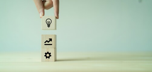 Concept building blocks: A hand carefully places an idea block atop a stack representing business growth and efficiency, symbolizing innovation, strategy, and progress.