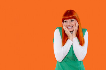 Brightly dressed woman smiles joyfully against an orange background, expressing excitement and happiness during a cheerful moment