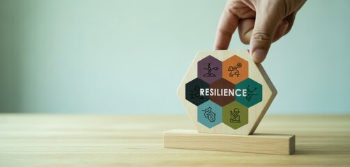 Resilience Strategy: A hand delicately balances a conceptual honeycomb structure displaying the word RESILIENCE atop a wooden platform.