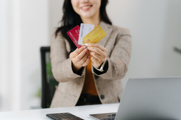 Payment Options: A professional businesswoman holds a selection of credit cards, showcasing diverse payment options in a modern business setting, while presenting a welcoming and friendly demeanor.