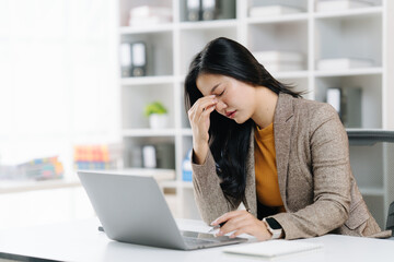 Burnout in the Office: A young, professional woman experiences the strain of workplace stress, as...